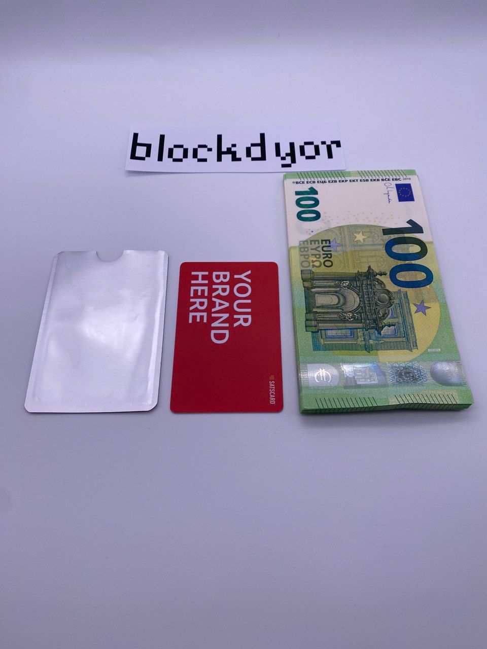 The RF-blocking sleeve (left), the SATSCARD (middle) and a bunch of cash for size comparison