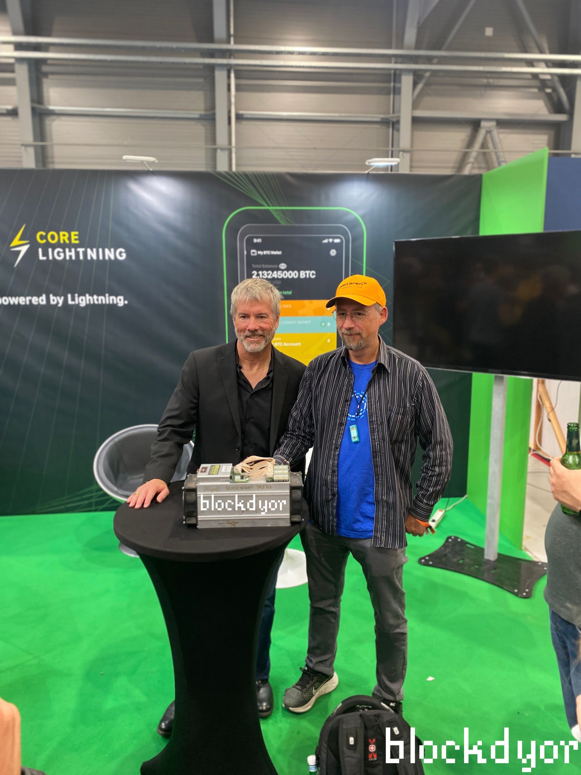 Michael Saylor and Adam Back in front of an Antminer at the Blockstream booth at BTC Prague